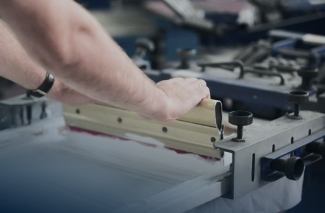 Utilisation d'une racle de sérigraphie par un opérateur de personnalisation textile